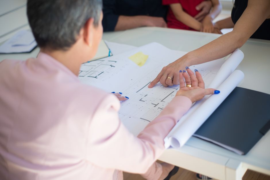 Group discussing architectural floor plans in an office setting.